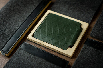 Handmade green wallet made of genuine leather on a wooden background. Close-up, top view.