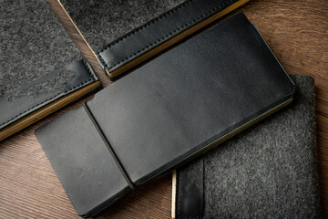 Handmade black wallet made of genuine leather on a wooden background. Close-up, top view.