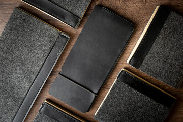 Fototapeta premium Handmade black wallet made of genuine leather on a wooden background. Close-up, top view.