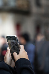 Hands of unrecognizable person taking a cell phone picture of the Barcelona Cathedral in Spain with blurred background