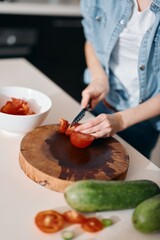 Fresh and Healthy: A Woman Cook Chopping Vegetables on a Wooden Board in the Kitchen