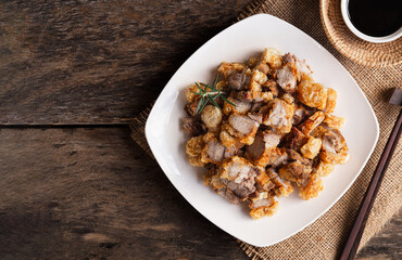 Top view of homemade crispy pork belly in white plate on wooden table background.