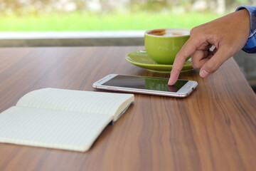 Close up of male finger touching smartphone screen in cafe