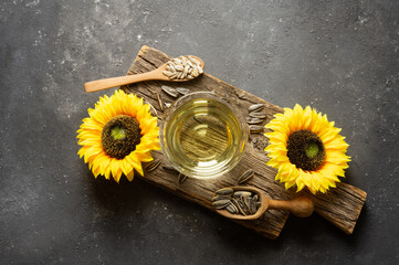 Glass bottle of sunflower seed oil with flowers on rustic background, cooking oil, helianthus annuus