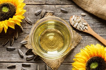 Glass bottle of sunflower seed oil with flowers on rustic background, cooking oil, helianthus annuus