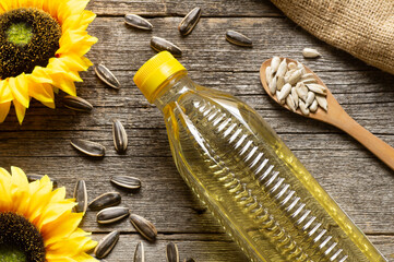 Glass bottle of sunflower seed oil with flowers on wooden rustic background, cooking oil,...