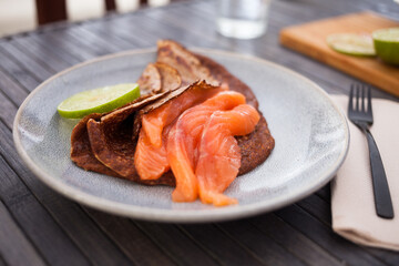 Salted salmon fillet with buckwheat pancakes and lime
