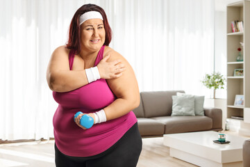 Plus size woman exercising and holding her painful shoulder