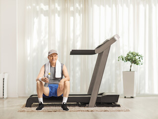 Elderly man resting on a treadmill at home