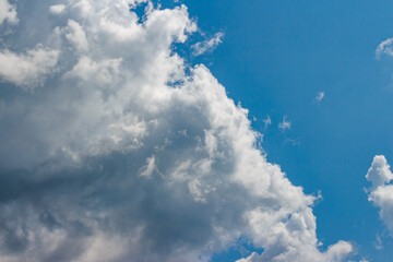 Large white cumulus cloud floating across the blue sky