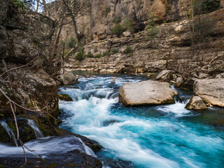 View from the shore of the fast flowing turquoise mountain river Koprucay in the Koprulu Canyon in Turkey. Beautiful water landscape. Large stones in the water, vertical mountains. Hiking concept