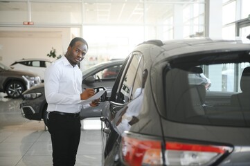 Cars Dealership Concept. Auto Seller Afro Man Standing In Automobile Center