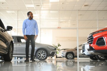 Fototapeta na wymiar His dream car. Happy young African man looking excited choosing a car at the dealership