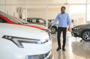 Handsome African man choosing a new car at the dealership