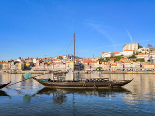 Embarcação tradicional em águas do Douro na Ribeira em Vila Nova de Gaia, com a velha cidade ao...