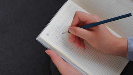 Woman making shopping list on a notebook. Business woman tick off with blue pencil on checklist or to do list box.