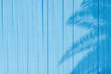 palm tree shadow cast on a vibrant blue wooden textured background. Summer concept.