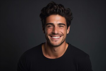 Obraz premium Portrait of a handsome young man smiling at the camera on a dark background.