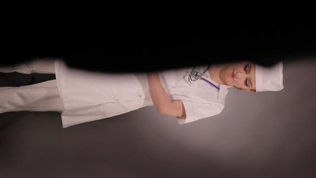 Emotional young woman doctor nurse in a white coat and hat