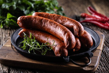 Pepper pork smoked sausages with rosemary in a cast iron pan