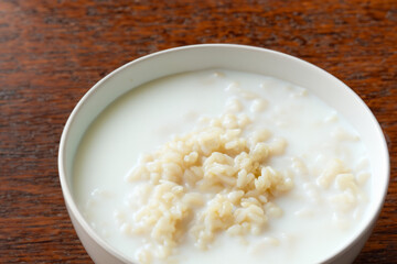 rice porrige. there is a white deep plate with milk rice porridge on a wooden table, breakfast concept