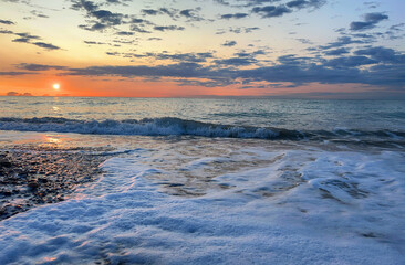 Pebble stone beach on sunrise. Sea beach shore with waves in ocean. Waves in sea on sunset. Empty coastline pebble beach. Sea beach landscape. Shore landscape on Spain resort. Ocean shoreline scenic.