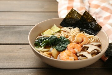 Delicious ramen with shrimps and mushrooms in bowl on wooden table, closeup with space for text. Noodle soup