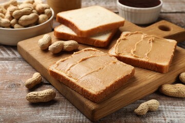 Fototapeta na wymiar Tasty peanut butter sandwiches and peanuts on wooden table, closeup
