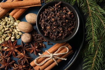Dishware with different spices, nuts and fir branches on table, top view