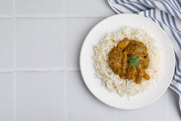 Delicious chicken curry with rice on white tiled table, top view. Space for text