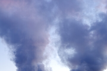 Thick gray smoke against a blue sky at sunset
