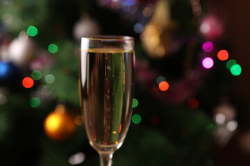 Christmas New Year background with Christmas tree lights and a glass of champagne. Soft focus.