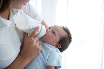 Asian mother feeding milk from bottle milk to her 19 days old baby,   food for infant concept