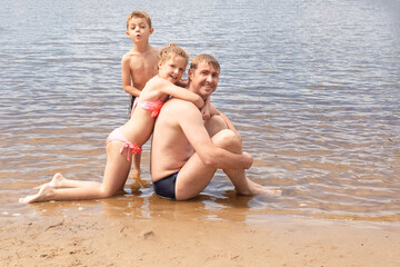 cheerful father with daughter and son playing on the beach. family having fun on vacation at the seaside