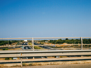 A clear blue sky overlooking cars on the asphalt of the main highway in Mallorca, Spain, from the vantage point of a bridge