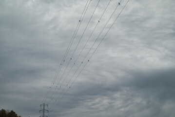 Low angle view of high voltage power lines over cloudy sky