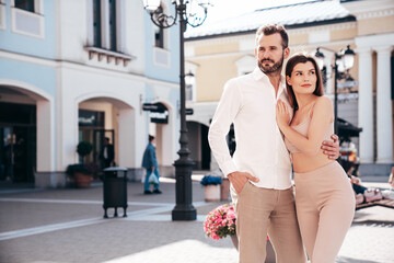 Beautiful fashion woman and her handsome elegant boyfriend in white shirt. Sexy brunette model in summer clothes. Fashionable smiling couple posing in street Europe. Brutal man and female outdoors
