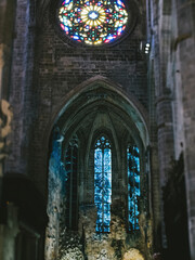 An interior view of the Catedral-Basilica de Santa Maia in Palma de Mallorca, showcasing the intricate gothic detailing and colorful stained glass windows under soft evening light.