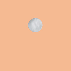 detail of a cotton disk for facial cleansing on peach fuzz background