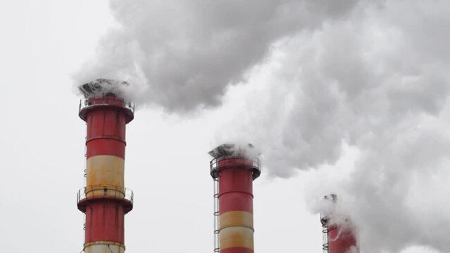 Industrial chimneys with heavy smoke causing air pollution on the gray sky background	
