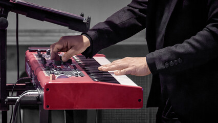 musician's hand on the keys of a red electrode piano