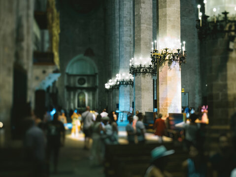 A group of unrecognizable people standing around the Catedral-Baslica de Santa Mara in Palma de Mallorca, Spain tilt-shift lens used