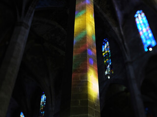 A photo of a tall column covered with multioclor light from the stained glass - featuring intricate stained glass windows in background - tilt-shift lens used