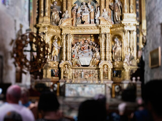 A group of unrecognizable people stands in awe before a stunning golden altar inside the Catedral-Baslica de Santa Maria in Palma de Mallorca, Spain.