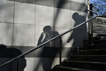 Shadows on the wall of two men coming down the steps