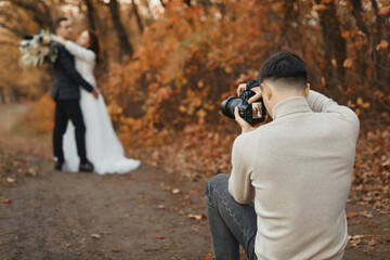 Professional wedding photographer in action. the bride and groom in nature in autumn