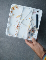 From a first-person perspective, a man moves towards the kitchen, carrying a tray with a broken spatula and scattered cake crumb