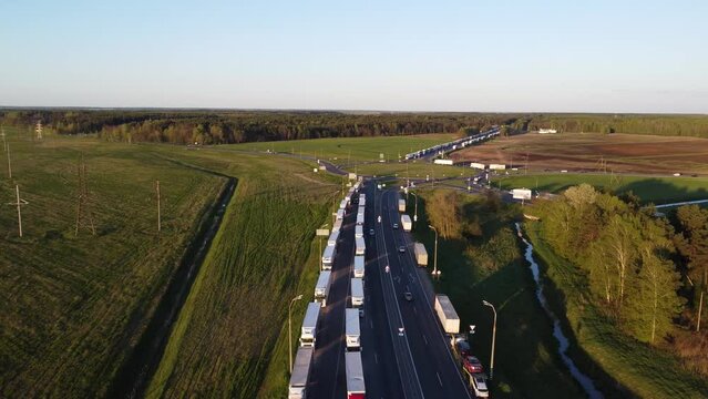 Top view of a line of trucks along the highway. Trucks in a traffic jam. The queue of lorrys before customs clearance of goods when crossing the border. Drone shot of a traffic intersection.