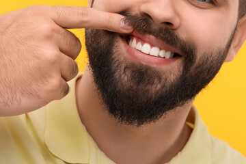 Obraz premium Man showing his clean teeth on yellow background, closeup