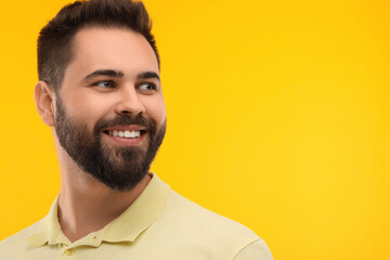 Obraz premium Man with clean teeth smiling on yellow background, space for text